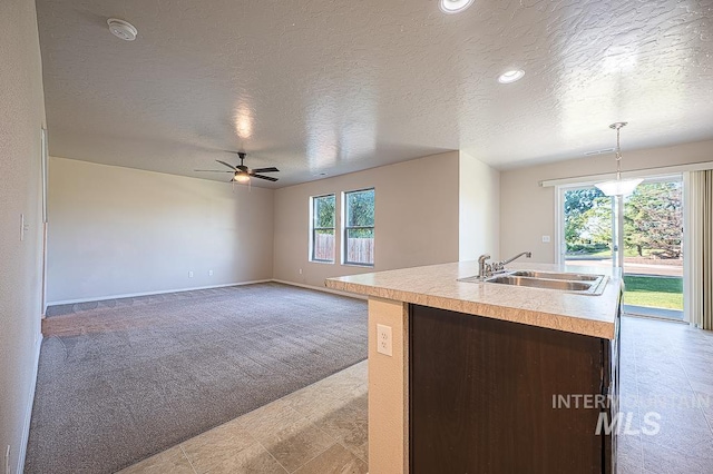 13513 Palm Bch, Caldwell, ID 83607 - kitchen with carpet, a textured ceiling, a ceiling fan, light countertops, and a center island with sink