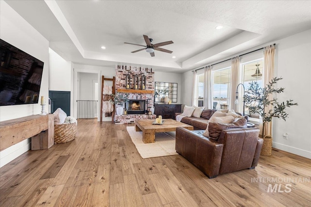 10935 Purple Sage Rd, Middleton, ID 83644 - living area with a tray ceiling, a ceiling fan, light wood-type flooring, and baseboards