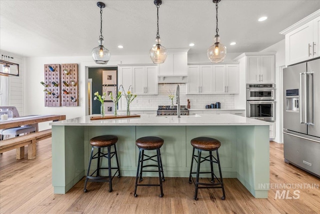 10935 Purple Sage Rd, Middleton, ID 83644 - kitchen with tasteful backsplash, light wood-style flooring, appliances with stainless steel finishes, and white cabinetry