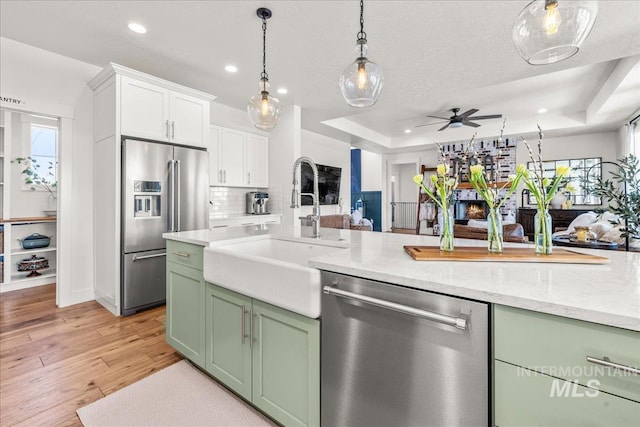 10935 Purple Sage Rd, Middleton, ID 83644 - kitchen featuring light wood finished floors, green cabinetry, stainless steel appliances, a raised ceiling, and a sink