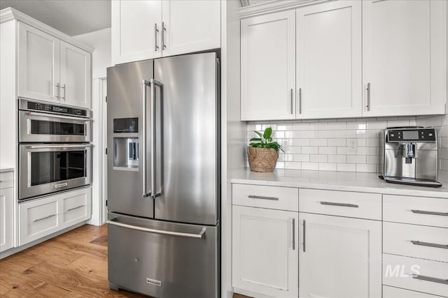 10935 Purple Sage Rd, Middleton, ID 83644 - kitchen with stainless steel appliances, tasteful backsplash, light wood-style flooring, and white cabinets