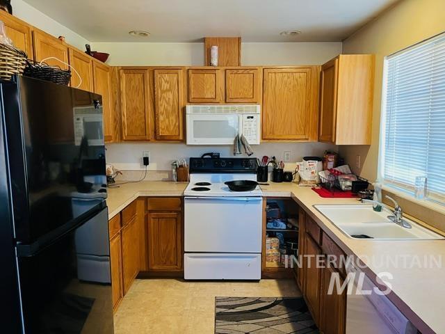 kitchen with a sink, white appliances, and light countertops