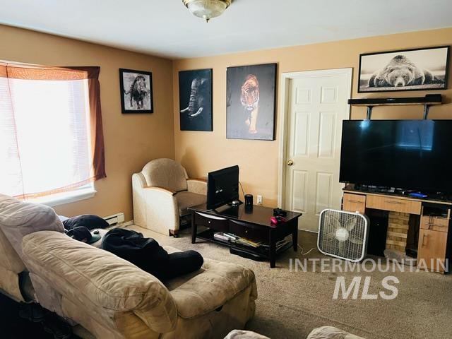 carpeted living area with a baseboard heating unit