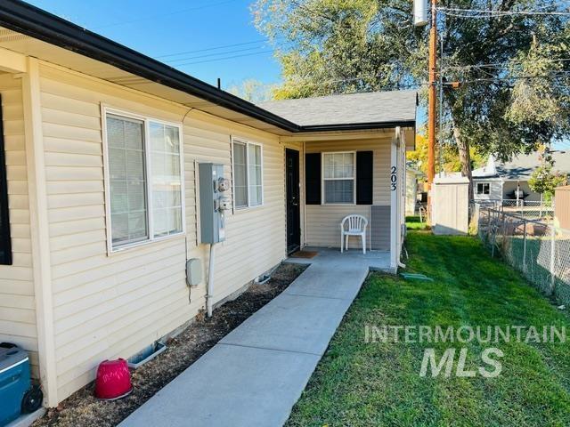 view of exterior entry with a yard and fence