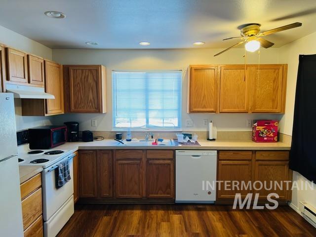 kitchen with under cabinet range hood, white appliances, light countertops, and a sink