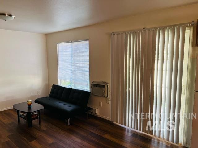 sitting room with an AC wall unit and wood finished floors