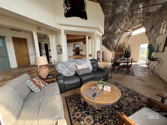 living area with visible vents and a towering ceiling