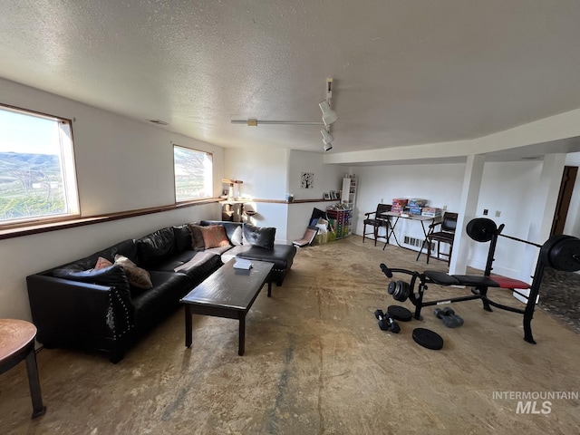 living room with track lighting, a textured ceiling, and visible vents