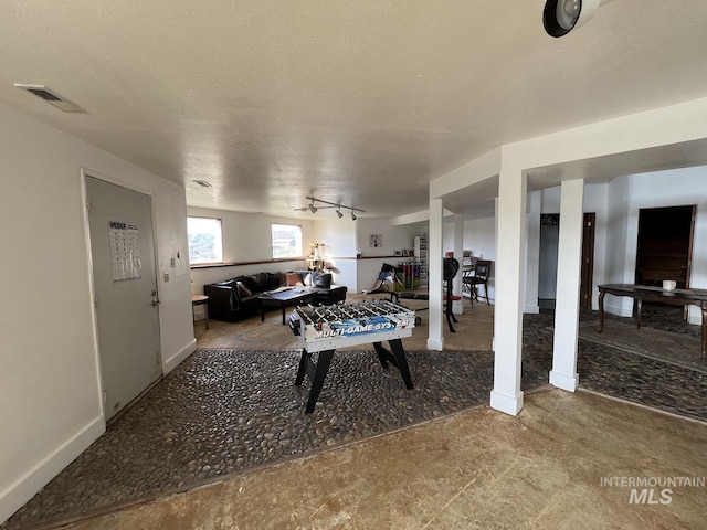 playroom featuring visible vents, baseboards, a textured ceiling, and track lighting