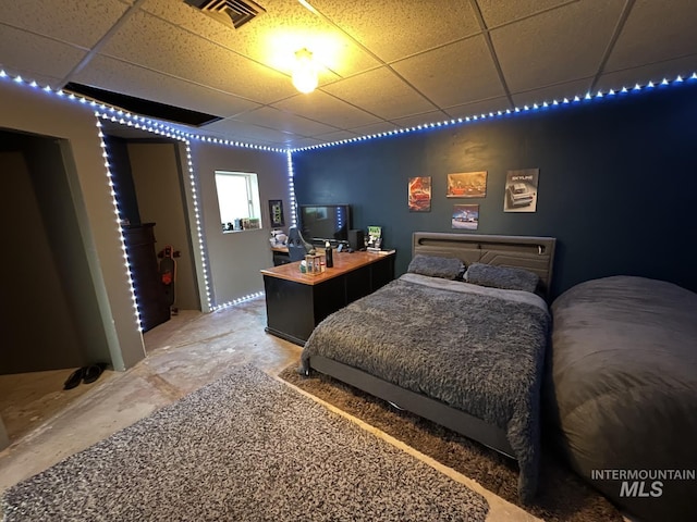 bedroom with unfinished concrete floors, visible vents, and a drop ceiling