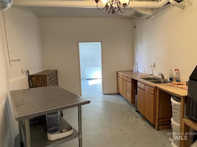 kitchen featuring a sink, concrete floors, brown cabinetry, and light countertops