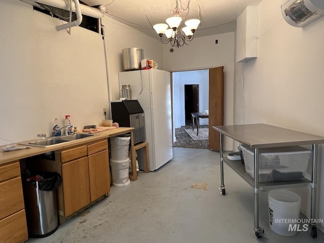 kitchen with brown cabinets, a sink, freestanding refrigerator, concrete floors, and a chandelier