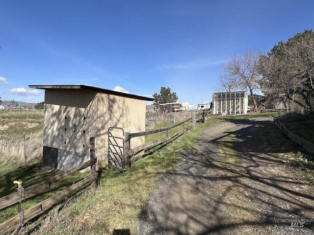 view of home's exterior with a rural view, an outdoor structure, and fence