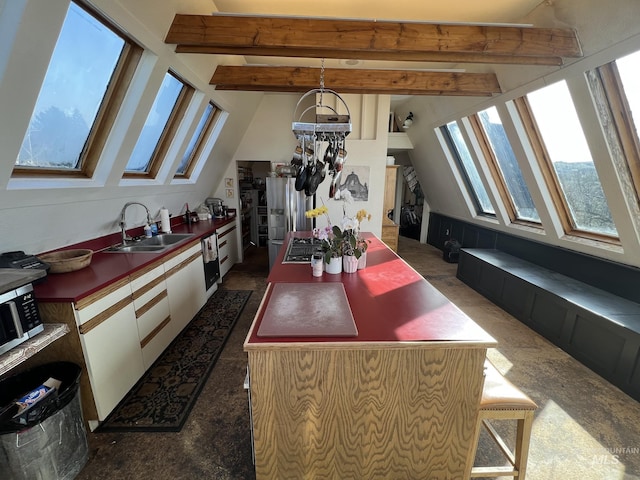 kitchen with white cabinets, vaulted ceiling with beams, stainless steel appliances, and a sink