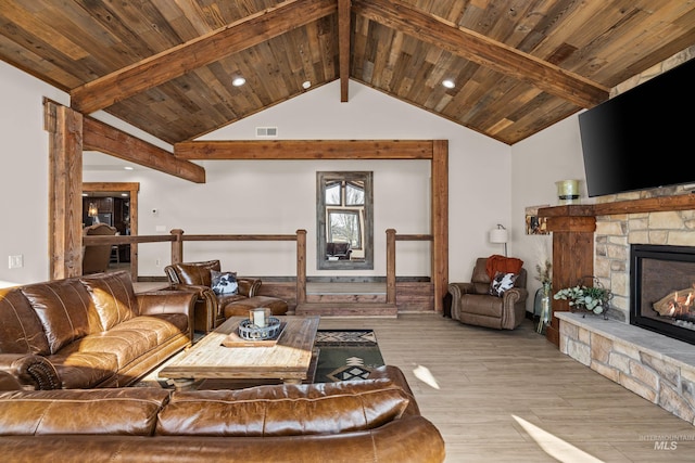 living room featuring lofted ceiling with beams, a stone fireplace, wooden ceiling, and light hardwood / wood-style flooring