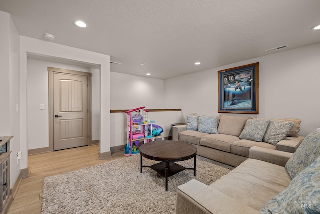 living room with a textured ceiling and light hardwood / wood-style floors