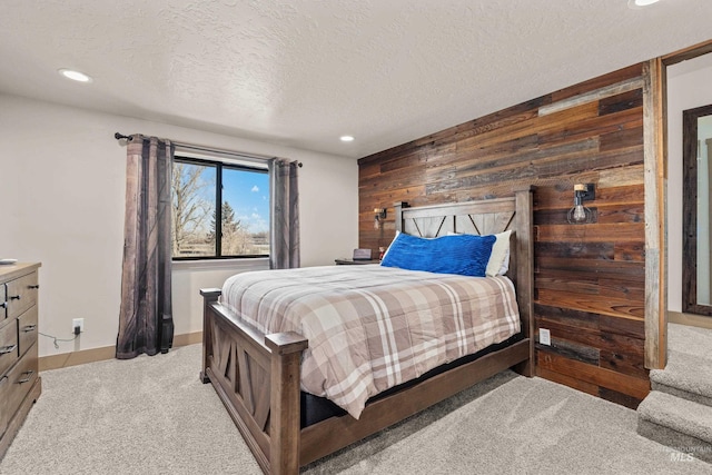 carpeted bedroom featuring wooden walls and a textured ceiling