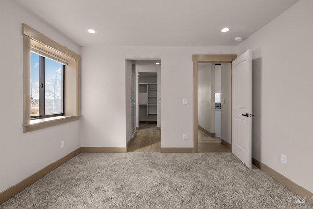 unfurnished bedroom with a walk in closet and light carpet