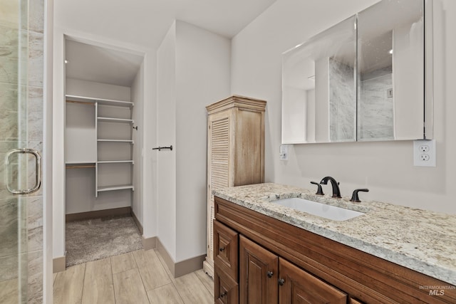 bathroom with a shower with door and vanity