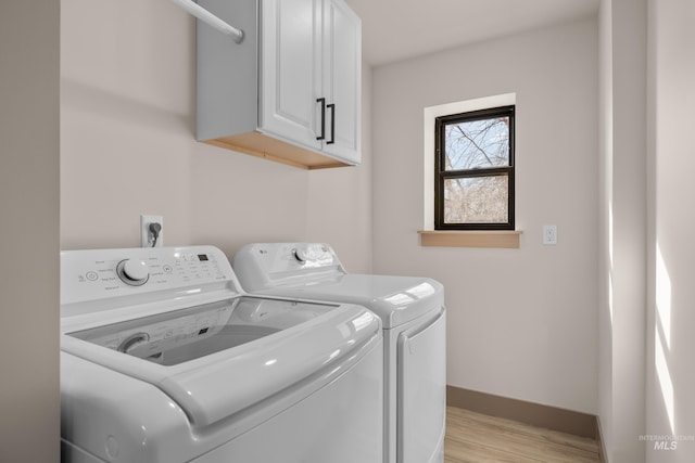 clothes washing area with light hardwood / wood-style flooring, cabinets, and washing machine and clothes dryer