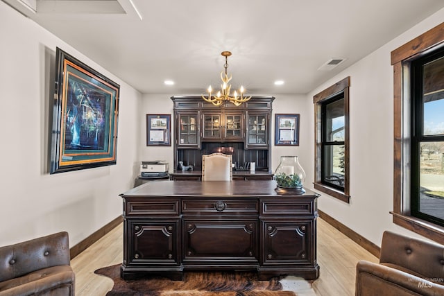 home office with an inviting chandelier and light hardwood / wood-style floors