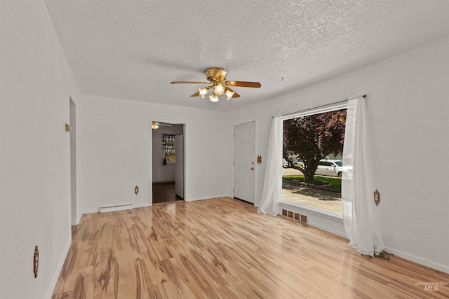 1402 Southside Blvd, Nampa, ID 83686 - spare room featuring baseboard heating, ceiling fan, light wood-style flooring, a textured ceiling, and baseboards