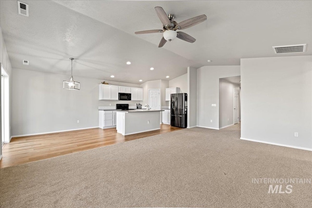 unfurnished living room with light carpet, vaulted ceiling, and ceiling fan