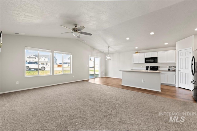 unfurnished living room with lofted ceiling, plenty of natural light, dark carpet, and ceiling fan with notable chandelier