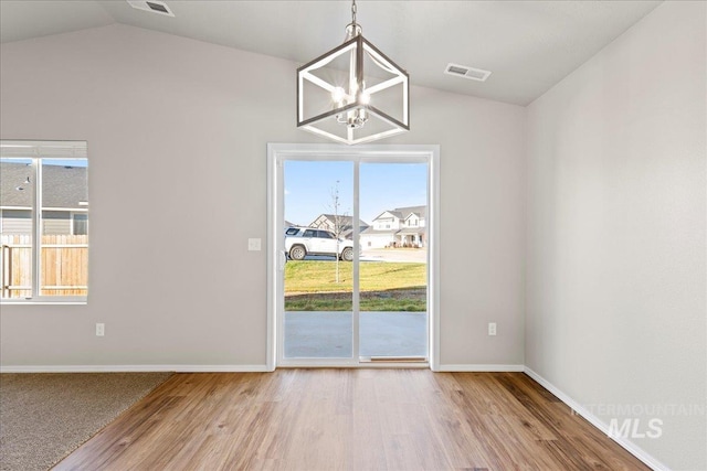 unfurnished dining area with vaulted ceiling, light hardwood / wood-style flooring, and an inviting chandelier