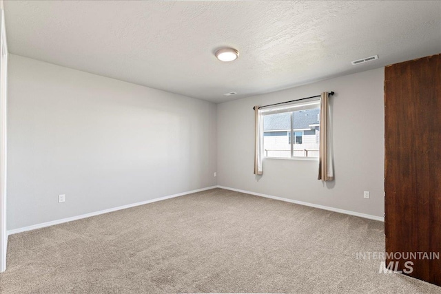 carpeted empty room featuring a textured ceiling