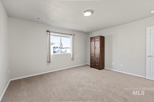 unfurnished bedroom with a textured ceiling and light carpet