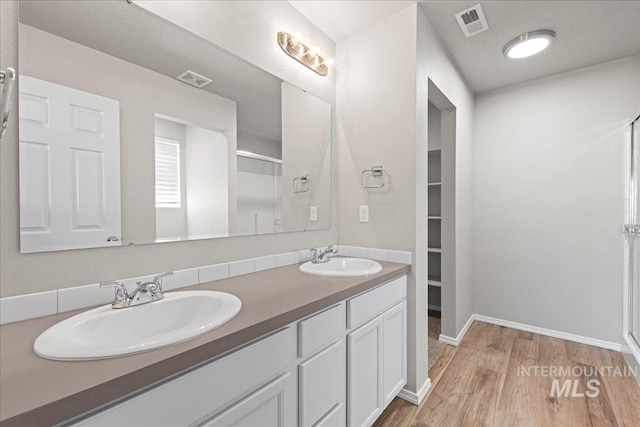 bathroom featuring hardwood / wood-style floors, vanity, and a shower with shower door