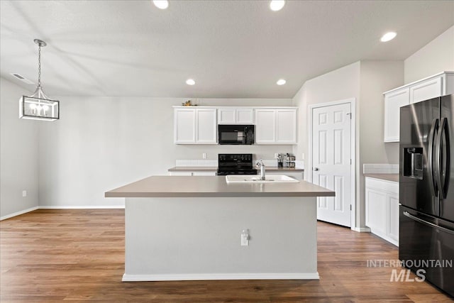 kitchen featuring black appliances, an island with sink, decorative light fixtures, white cabinetry, and wood-type flooring