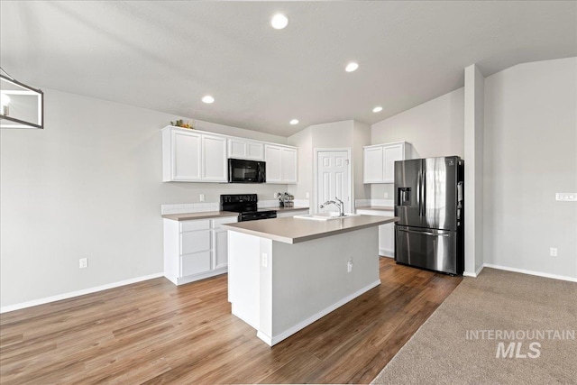 kitchen with sink, a center island with sink, white cabinets, black appliances, and hardwood / wood-style flooring