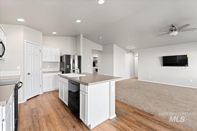 kitchen with black dishwasher, stainless steel fridge with ice dispenser, a kitchen island with sink, and white cabinetry