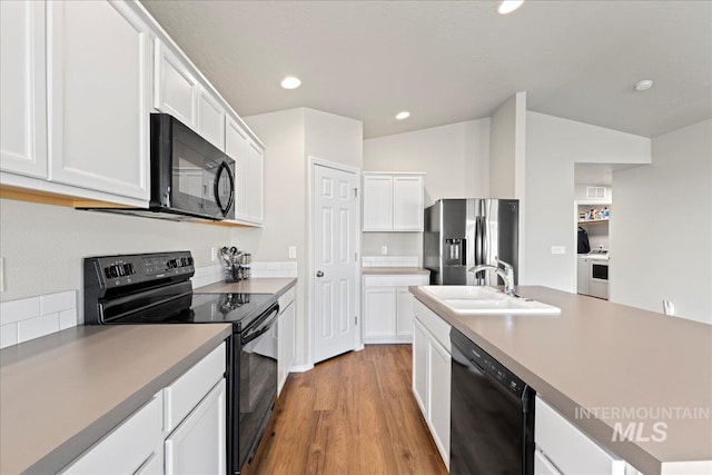 kitchen featuring black appliances, sink, vaulted ceiling, light wood-type flooring, and white cabinetry