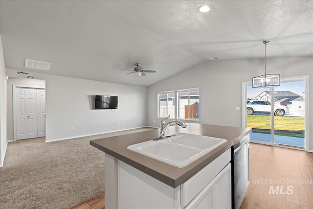 kitchen with stainless steel dishwasher, a textured ceiling, sink, white cabinetry, and an island with sink