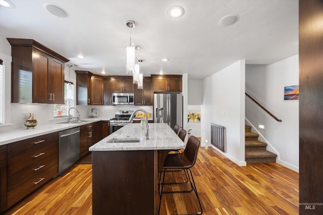 1309 S Pacific St, Boise, ID 83705 - kitchen with stainless steel appliances, wood finished floors, a breakfast bar, a kitchen island with sink, and recessed lighting