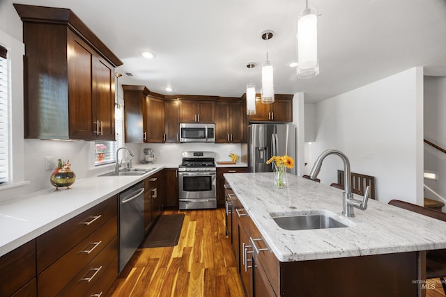 1309 S Pacific St, Boise, ID 83705 - kitchen with stainless steel appliances, wood finished floors, an island with sink, decorative light fixtures, and light stone counters