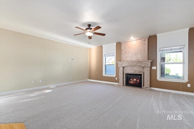 unfurnished living room with a ceiling fan, light carpet, baseboards, and a fireplace