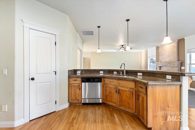 kitchen with stainless steel dishwasher, brown cabinetry, a sink, light wood-type flooring, and dark stone countertops