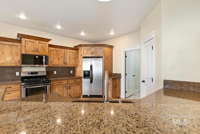 kitchen with appliances with stainless steel finishes, dark stone countertops, decorative backsplash, and recessed lighting