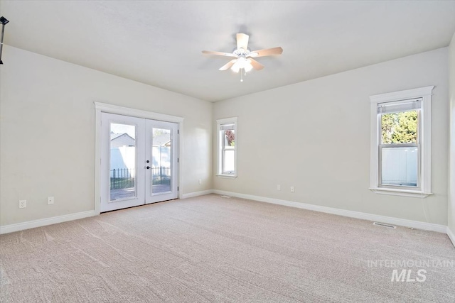 spare room featuring french doors, light colored carpet, a ceiling fan, and baseboards