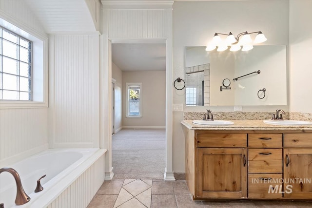bathroom featuring tile patterned floors, a garden tub, double vanity, and baseboards