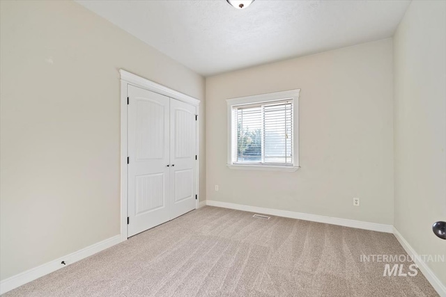 unfurnished bedroom featuring carpet, baseboards, and a closet