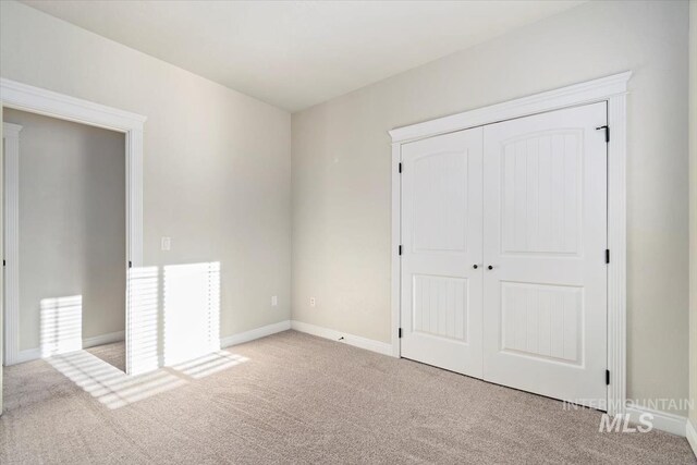 unfurnished bedroom with carpet, a closet, and baseboards