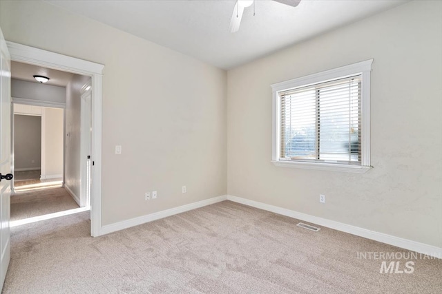 carpeted empty room featuring ceiling fan and baseboards