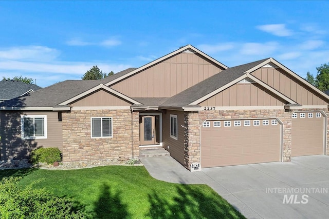 view of front of property featuring stone siding, an attached garage, a front lawn, driveway, and a shingled roof