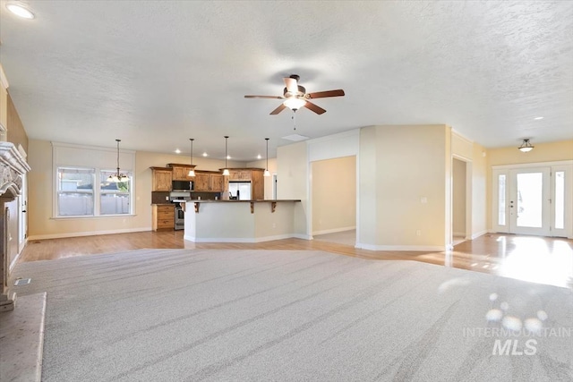 unfurnished living room featuring baseboards, ceiling fan, a textured ceiling, light colored carpet, and recessed lighting