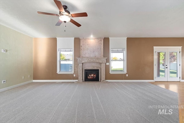 unfurnished living room with ceiling fan, plenty of natural light, and baseboards